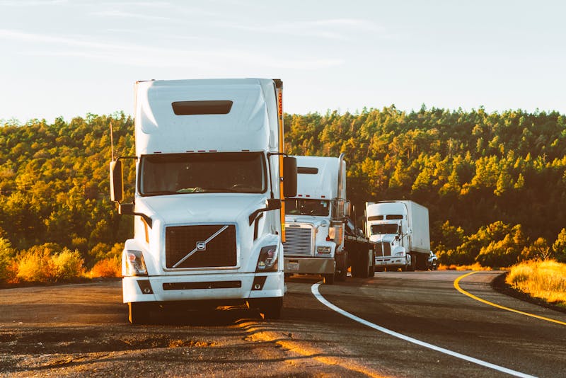 Vrachtwagens op een Europese snelweg met uitlaatgassen die de impact van CO2-uitstoot op transportkosten symboliseren