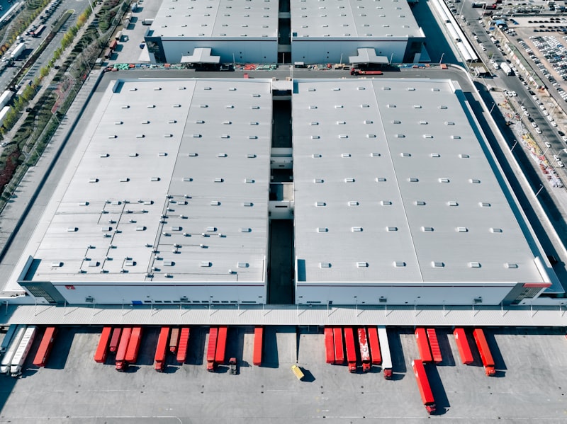 Luchtfoto van distributiehallen en vrachtwagenplaatsen als illustratie van terreinindeling, laadinfra-ontwerp en energieplanning voor een transportlocatie