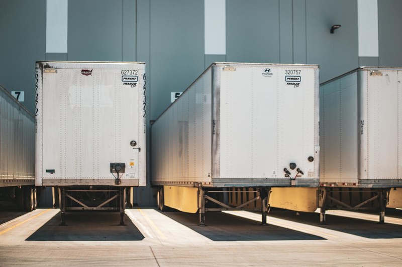 Vrachttrailers aan laaddocks bij een logistiek depot als illustratie van truckritten, tijdvensters en flexibel laadvermogen binnen congestiemanagement
