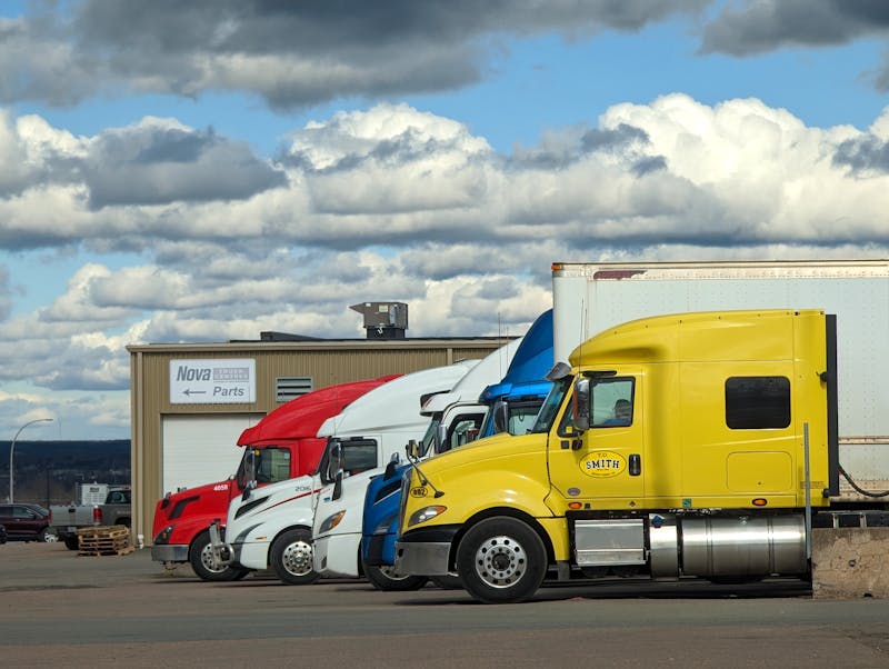 Meerdere vrachtwagens geparkeerd bij een warehouse als illustratie van vlootbeschikbaarheid, depotoperatie en het afwegen van flexibiliteit tegen vertrekzekerheid